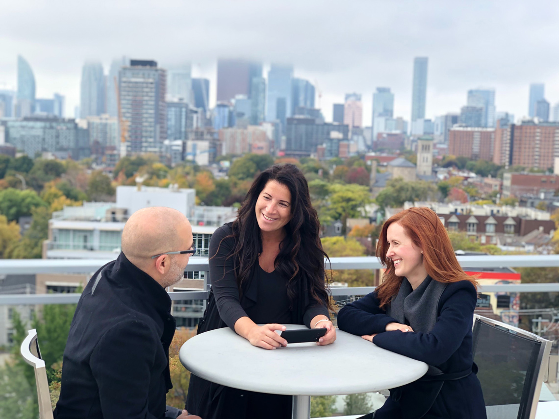 Dean, Danielle, and Kimsha on a Toronto rooftop with the city skyline