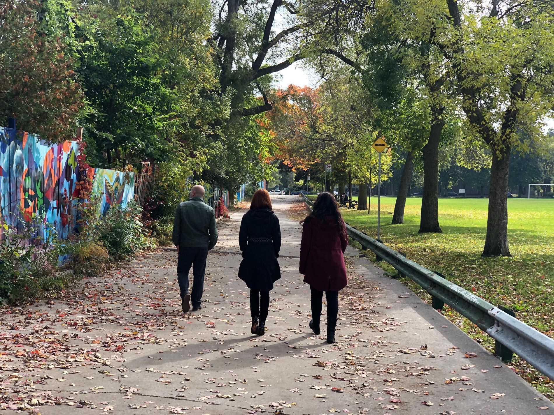 The We Know Houses team walking through a tree-lined Toronto neighbourhood in autumn